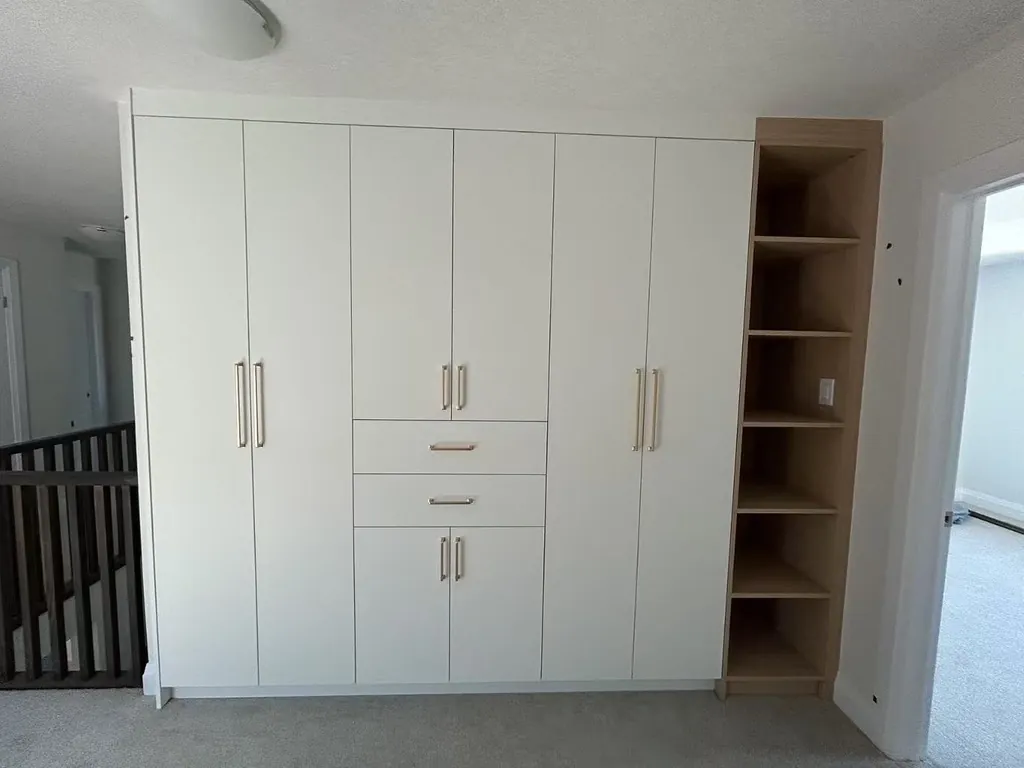 Custom wardrobe wall with drawer tower by Newood Millwork
