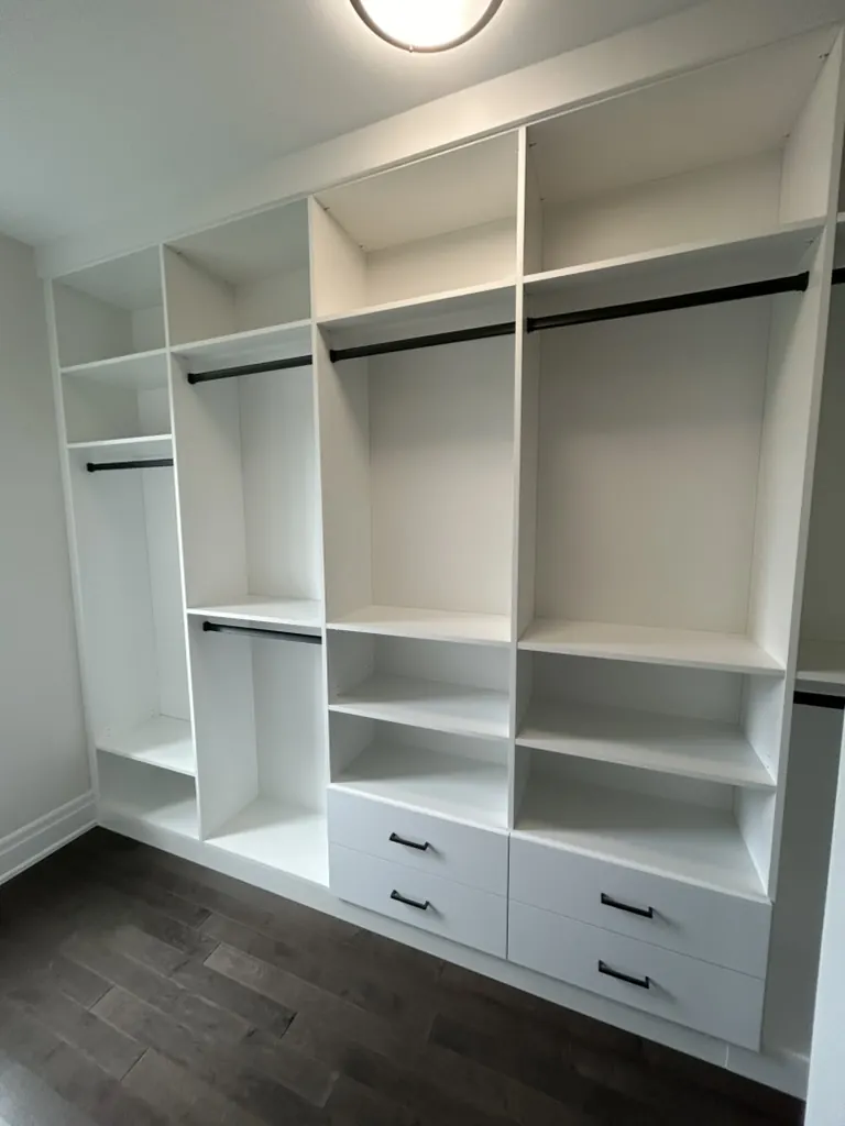 Open custom closet system with hanging rods and shelving by Newood Millwork