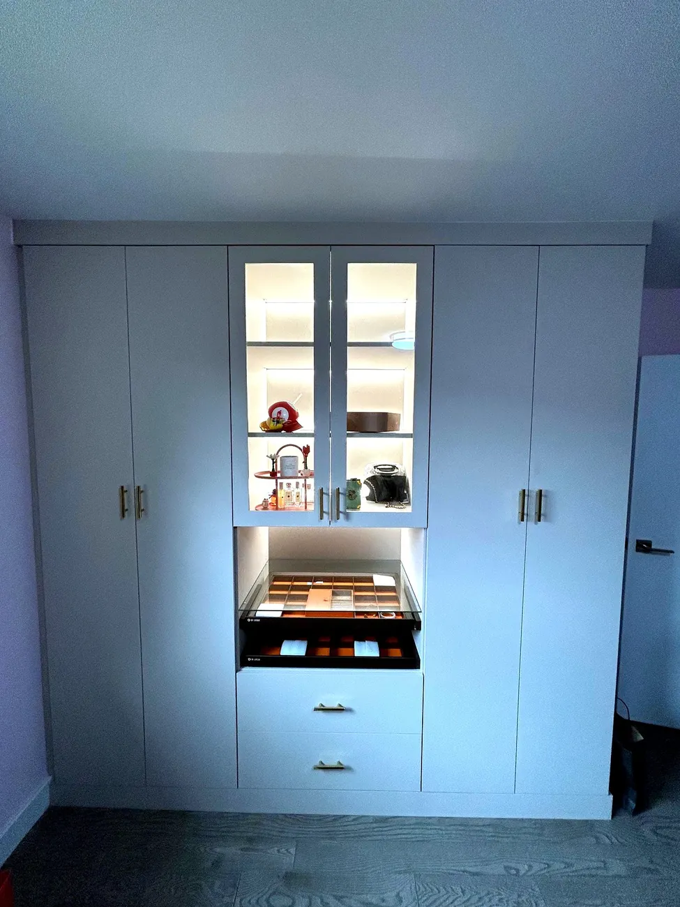 Custom built-in wardrobe with lit glass display cabinet by Newood Millwork
