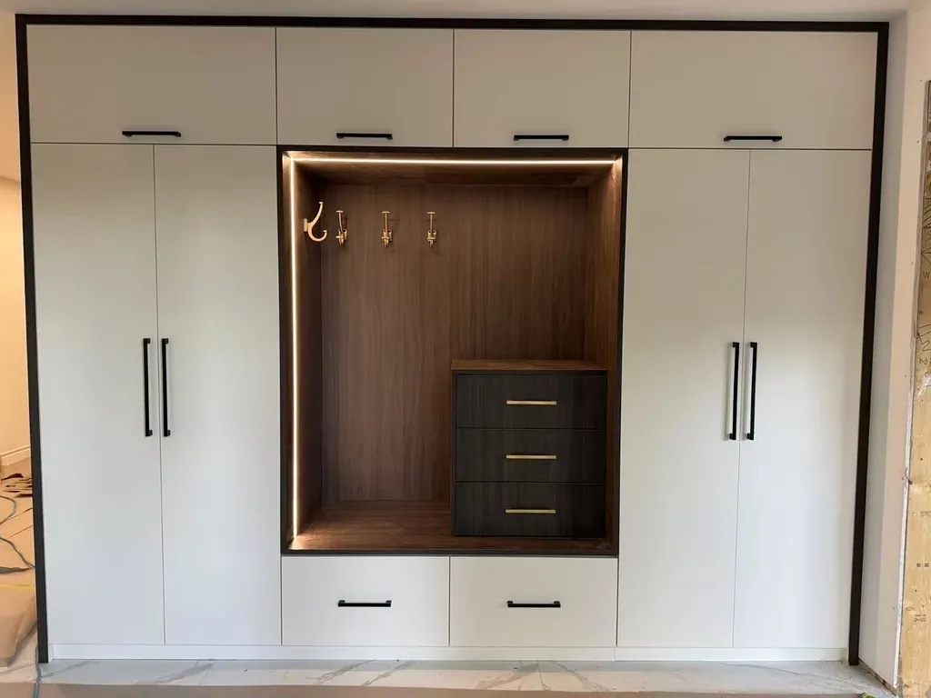Custom mudroom drop-zone with lit wood nook and brass hardware by Newood Millwork