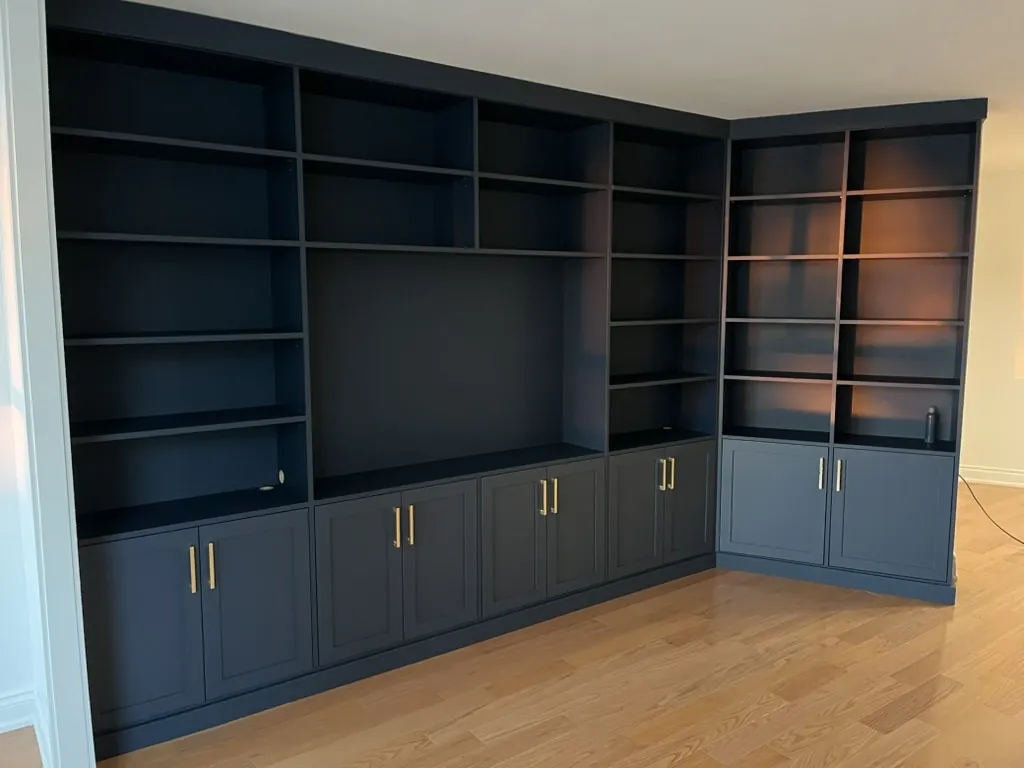 Custom navy built-in bookshelf with brass hardware by Newood Millwork