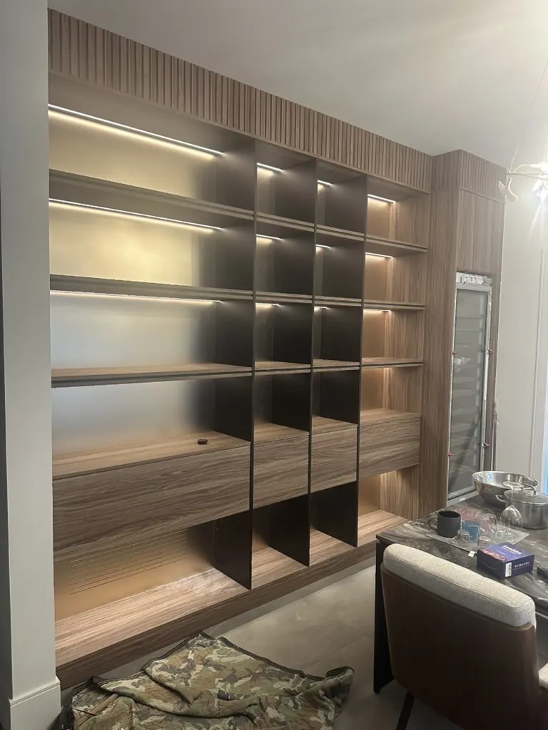 Custom wood shelving with integrated lighting by Newood Millwork